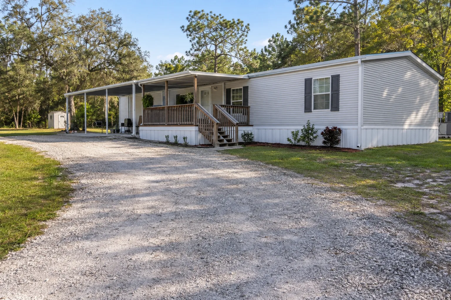 Gravel driveway and staging area beside a double-wide manufactured home